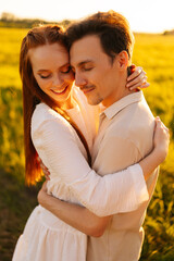 Wall Mural - vertical portrait of romantic young couple in love hugging, kissing standing together on green meado