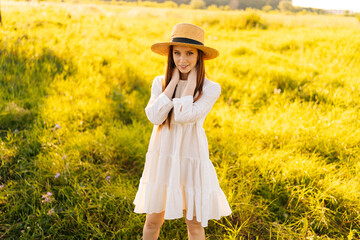 Wall Mural - portrait of cute redhead happy young woman wearing straw hat and white dress standing posing on beau