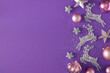 New Year eve concept. Flat lay composition of silver deer, pink baubles, stars and sequins on violet background with copy space. Creative holiday card idea.
