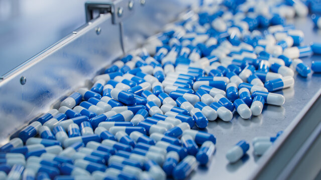 blue capsules are moving on conveyor at modern pharmaceutical factory. tablet and capsule manufactur