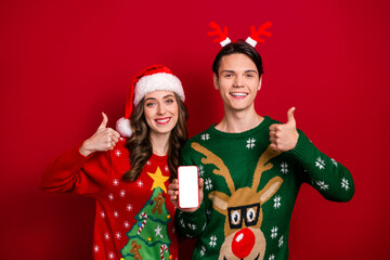 Poster - Portrait of two beautiful partners showing empty space telephone touch screen thumb up advice isolated on red color background