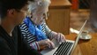 © Robert Peak - Closeup of elderly senior woman learning to use a laptop computer from teen male grandson with tea.