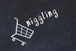 Chalk drawing of shopping cart and word niggling on black chalboard. Concept of globalization and mass consuming