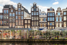 Amsterdam Floating Flower Market And Tall Narrow Historic Canal Houses Along The Singel In The Center Of The Capital.