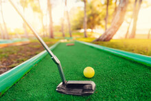 Yellow Ball With Stick For Sports Mini Golf On Green Grass Background With Sunlight
