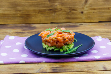 Wall Mural - Salmon tartare with avocado and arugula on wooden table