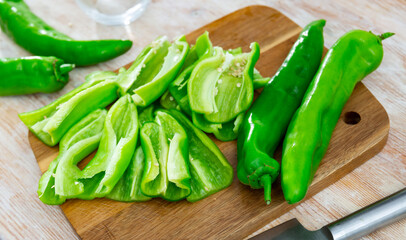 Wall Mural - Green capsicum chopped on cutting board. Sliced fresh vegetables as food ingredient.