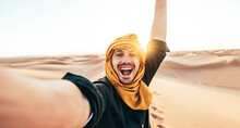 Happy Male Tourist Taking Selfie On Sand Dunes In The Africa Desert, Sahara National Park - Influencer Travel Blogger Enjoying Trip While Takes Self Portrait - Summer Vacation And Weekend Activities