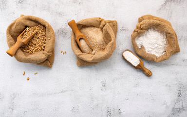 Wheat ears and wheat grains set up on white stone background.