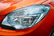 Closeup Of Headlamp On Red Car. Front Headlight Of Modern Auto