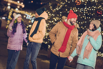 Canvas Print - Portrait of group positive satisfied partners hold arms walking chatting conversation garland lights outside