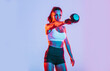 © oneinchpunch - Artistic image with colored gel lights of a beautiful fit woman making exercises in the gym with sport equipments and gear