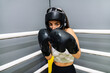 Woman with protective gloves and headgear in attack position on a ring boxing