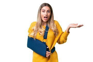 Sticker - Young Uruguayan woman with broken arm and wearing a sling over isolated background with shocked facial expression