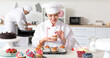 Female confectioner decorating tasty cupcakes in kitchen