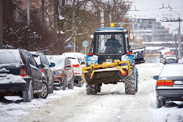 Wall Mural - Tractor with snow plow and rear brush removing snow from road during snow storm, road maintenance at winter season. Tractor clean road and remove snow and ice from parking lot