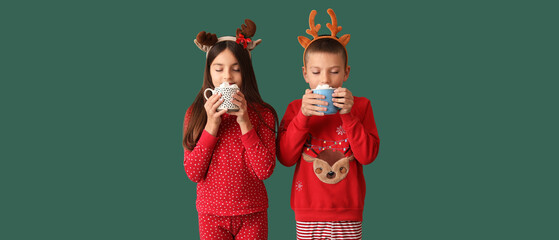 Sticker - Cute children in Christmas pajamas drinking hot chocolate on green background