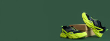 Cardboard Box With Stylish Running Shoes On Green Background With Space For Text