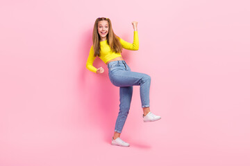 Poster - Full length photo of lucky excited school girl dressed yellow crop top walking rising fists isolated pink color background