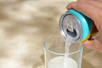 Wall Mural - Woman pouring drink from aluminum can into glass at table, closeup. Space for text