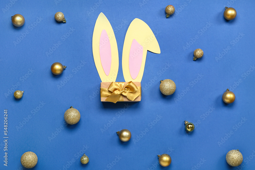 Bunny ears with Christmas balls and gift on blue background