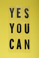 Phrase Yes You Can with of plastic letters on yellow background, top view. Motivational quote