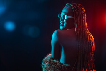 Wall Mural - Black ethnic woman with braids with blue and red led lights, model from the back, sensual pose looking