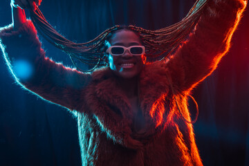 Wall Mural - Black ethnic woman with braids with blue and red led lights, moving her hair while dancing