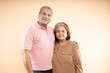 © GAJENDRRA BHATI  - Portrait of Happy indian senior couple standing together over beige background. Old Asian man and woman smiling.