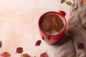 Poster - Cup of hot drink, leaves and soft knitted fabric on beige textured table, space for text. Cozy autumn atmosphere