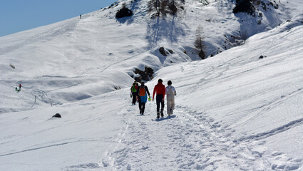 Wall Mural - a family walks in the snow in the high mountains on a beautiful sunny winter day