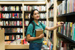 © AntonioDiaz - Beautiful college student browsing in the bookshelves at the bookstore