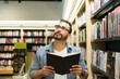 © AntonioDiaz - Happy man enjoying an exciting book while reading at the bookstore