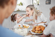 © L Ismail/peopleimages.com - Happy family, mother and child eating chicken and vegetables in a healthy meal for dinner in Germany, Berlin. Food, nutrition and young girl feeding her hungry mom lunch at a home dining room table