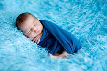 Wall Mural - Cute baby boy, peacefully sleeping wrapped in blue wrap