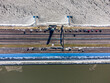 On a cold winterday we see the IJsselmeer completely frozen while the Wadden sea is still liquid. The highway runs along this long dike in The Netherlands with a bright blue sky. Drone shot, topdown