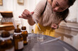 © ADDICTIVE STOCK - Female master dripping essential oil into glass bottle at home
