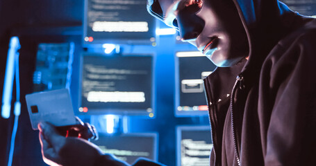 A hacker wearing a mask to cover his face is using computer to hack data to get ransom from victims.