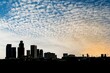 Skyline of Los Angeles downtown silhouette against a blue sky with scattered clouds at sunset