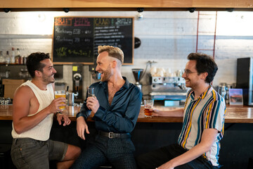 LGBTQ Friends sit at a bar with beer and champagne