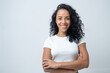 © Jirus - Portrait of smiling latin woman with curly hair with crossed arms isolated on grey background.