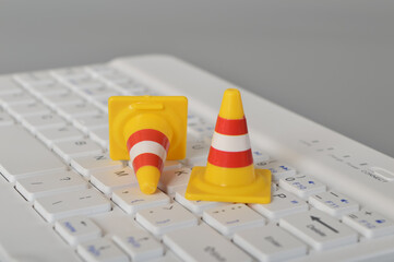 Traffic cones and laptop keyboard.Computer system under construction, repair and maintenance concept.