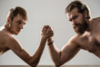 © Yevhen - Arm wrestling. Heavily muscled bearded man arm wrestling a puny weak man. Arms wrestling thin hand, big strong arm in studio. Two man's hands clasped arm wrestling, strong and weak, unequal match