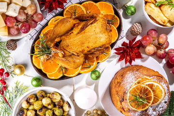 Wall Mural - Christmas or New Year dinner foods on white wooden table. Set of traditional Xmas party dishes - pannetone, baked chicken, vegetables, potato, cheese and fruits plate, top view copy space