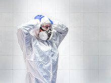 Scientist Wearing A Protective Suit And Face Mask With Hands On Head