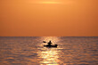 © bilanol - Dark figure of sportsman rowing alone on his kayak boat on sea water at sunset. Active extreme sports concept