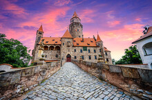 Bouzov Castle. Fairytale Castle In Czech Highland Landscape. Castle With White Church, High Towers, Red Roofs, Stone Walls. Czech Republic.