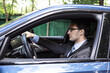 © Vitaliy - Handsome businessman in black suit driving in luxury car