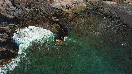 Wall Mural - Wild volcanic calm ocean beach waves crashing on sand and stones rocky shore. Emerald azure clear water. Aerial top down footage. Nobody.