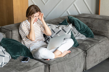 Overworked attractive woman has a headache after busy work day at home